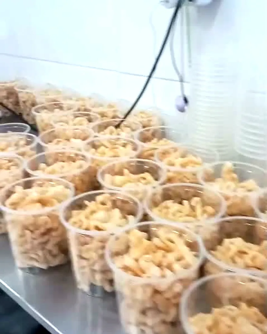 Potes de pururuca sendo enchidos na linha de produção da Amendoísio.